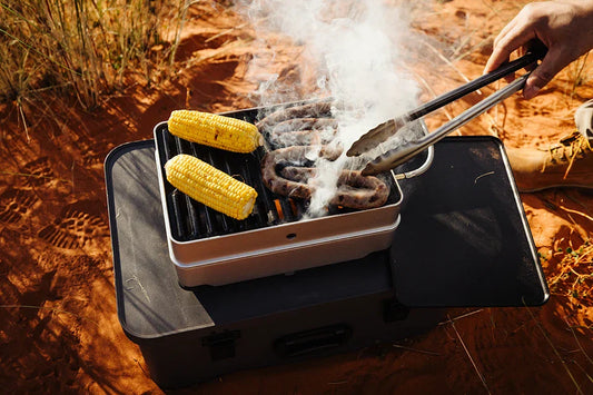 Enders Pace beim Camping-Grillen, mit Fleisch und Maiskolben