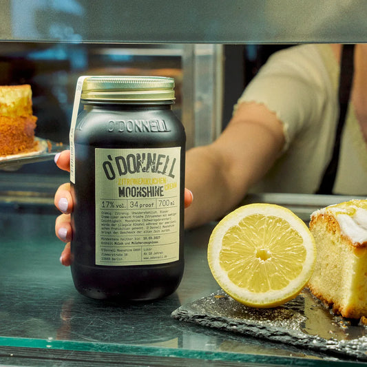 O´Donnell Moonshine Zitronenkuchen Cream Mason Jar Glas neben einer Zitronen und Kuchen